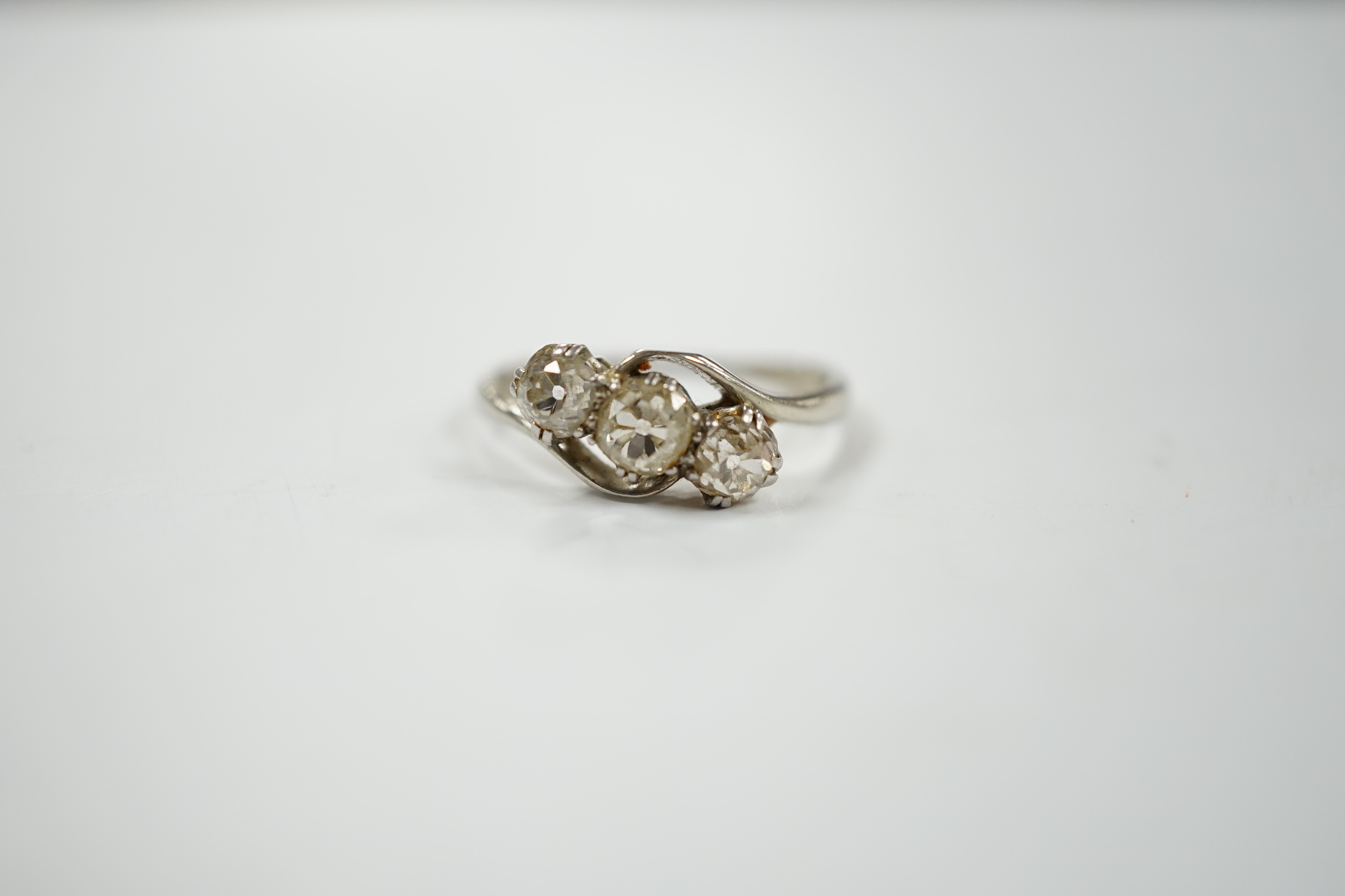 An 18ct, plat and three stone old mine cut diamond set crossover ring, size N, gross weight 2.3 grams.
